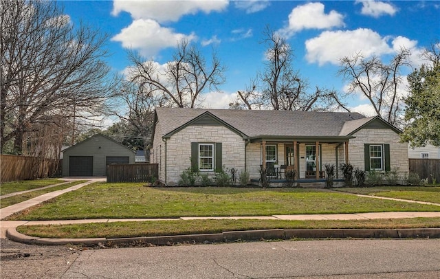 single story home with a porch, a garage, an outbuilding, and a front lawn