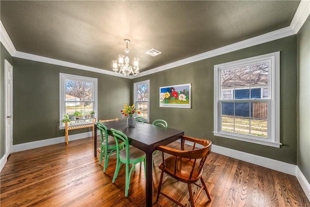 dining space with ornamental molding, a chandelier, a textured ceiling, and hardwood / wood-style flooring