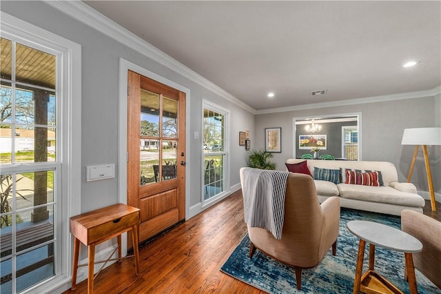 living room with wood-type flooring, ornamental molding, and a notable chandelier