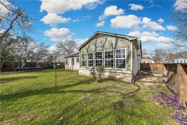 back of house featuring a lawn and a trampoline