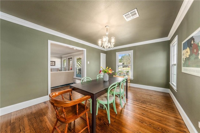 dining room featuring a textured ceiling, hardwood / wood-style flooring, crown molding, and a notable chandelier