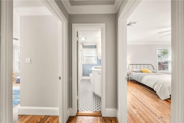 hallway featuring crown molding and light hardwood / wood-style flooring