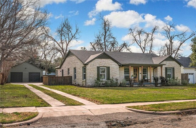 ranch-style home with an outbuilding, a front lawn, covered porch, and a garage