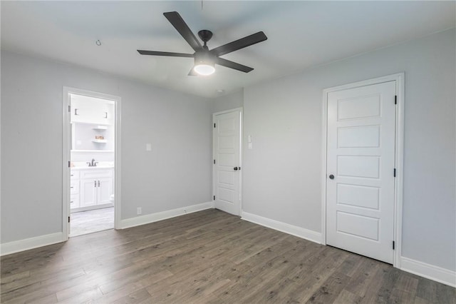 unfurnished bedroom featuring ceiling fan, ensuite bathroom, dark hardwood / wood-style flooring, and sink