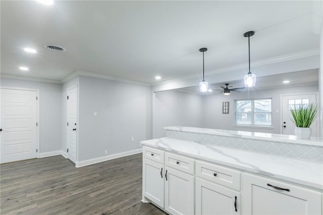 kitchen with pendant lighting, ornamental molding, light stone countertops, and white cabinets