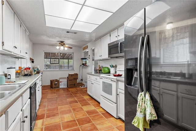 kitchen with appliances with stainless steel finishes, a textured ceiling, ceiling fan, sink, and white cabinetry