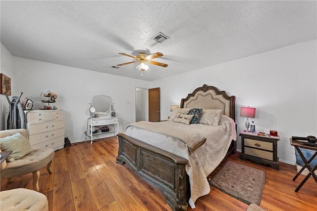 bedroom with hardwood / wood-style flooring, ceiling fan, and a textured ceiling