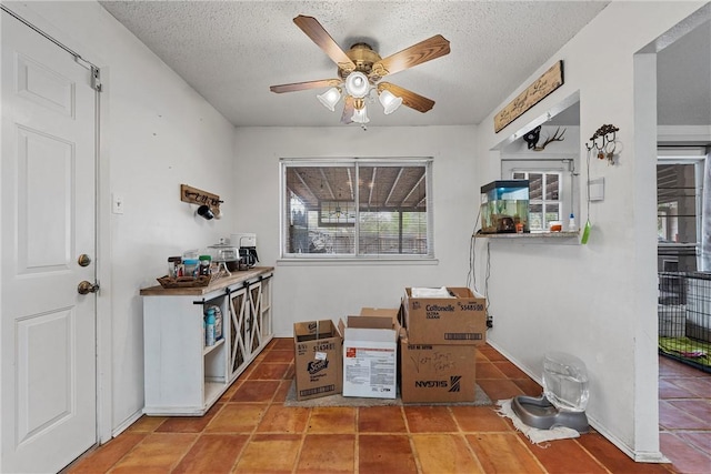 interior space with tile patterned flooring, ceiling fan, and a textured ceiling