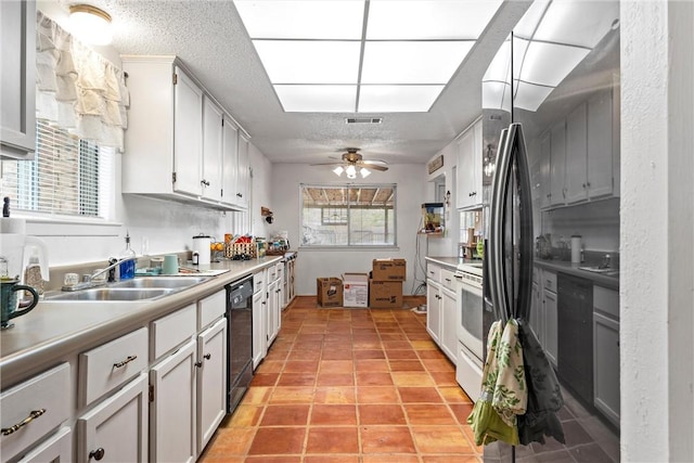 kitchen with ceiling fan, sink, black dishwasher, light tile patterned flooring, and white cabinets