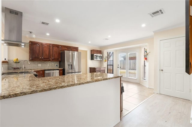 kitchen with decorative backsplash, light hardwood / wood-style floors, light stone counters, kitchen peninsula, and stainless steel appliances