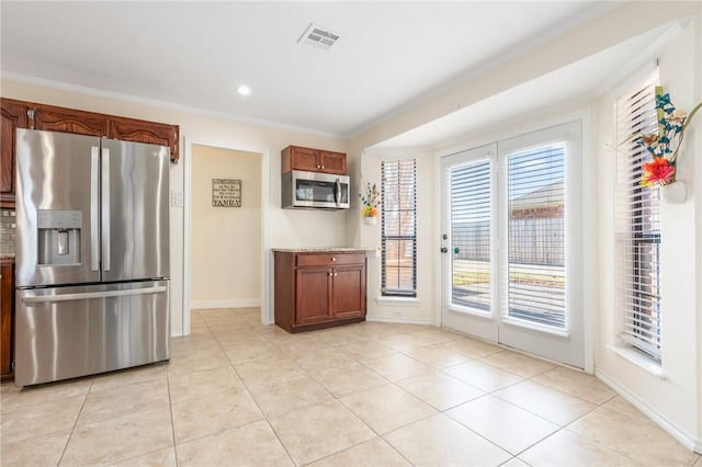 kitchen featuring light tile patterned flooring, ornamental molding, and appliances with stainless steel finishes