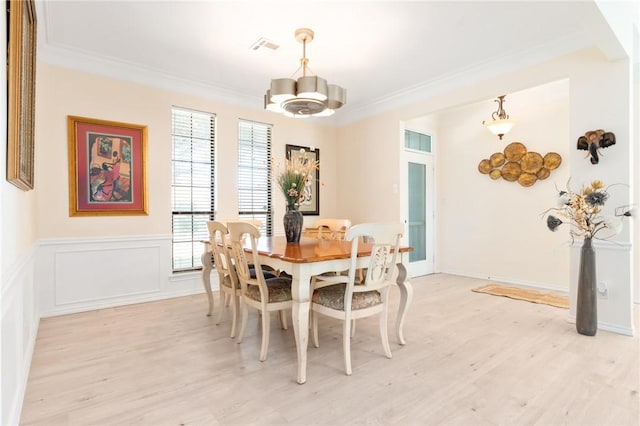 dining area with light wood-type flooring, crown molding, and a chandelier