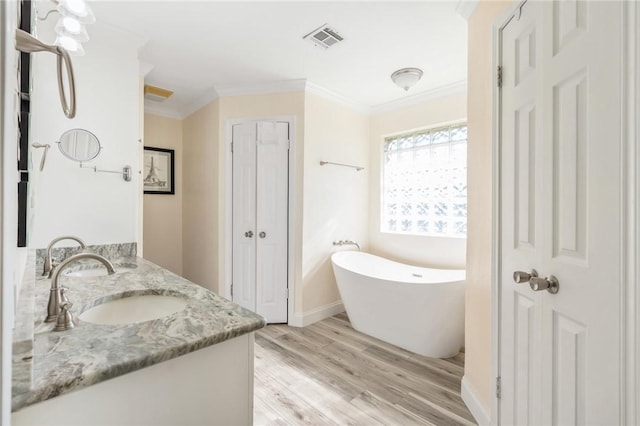 bathroom featuring hardwood / wood-style floors, vanity, a tub to relax in, and crown molding