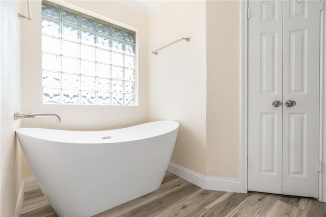 bathroom with a tub to relax in and wood-type flooring