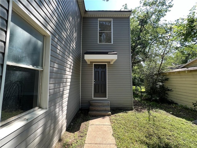 view of exterior entry featuring a lawn