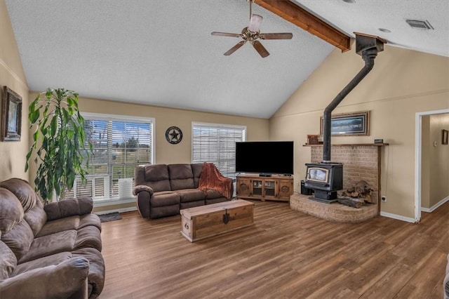 living room with a wood stove, ceiling fan, high vaulted ceiling, hardwood / wood-style floors, and a textured ceiling