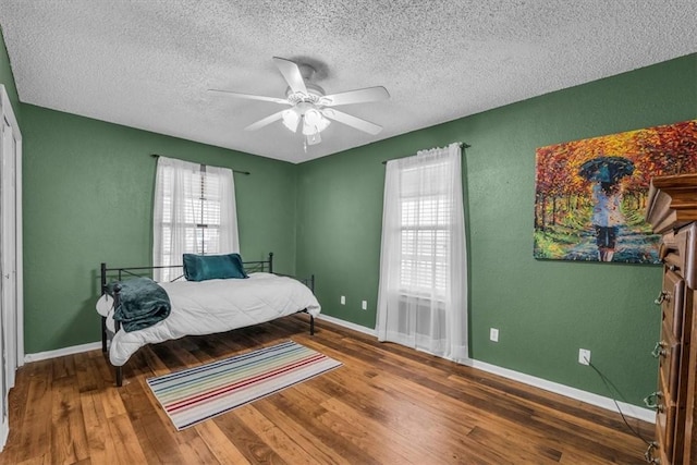 bedroom with ceiling fan, wood-type flooring, and a textured ceiling