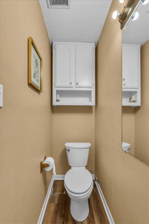 bathroom featuring toilet, wood-type flooring, and a textured ceiling