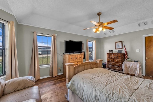 bedroom featuring ceiling fan, wood-type flooring, a textured ceiling, and ornamental molding