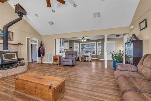 living room with high vaulted ceiling, hardwood / wood-style flooring, a wood stove, and ceiling fan