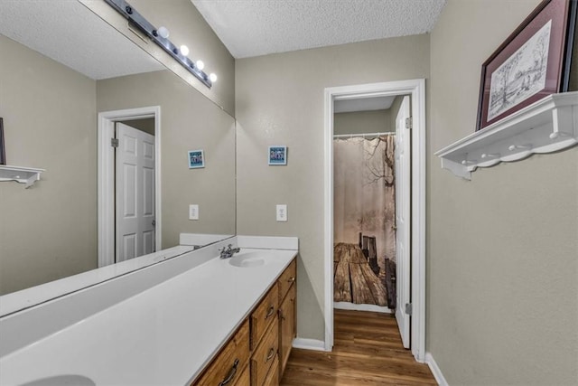 bathroom with hardwood / wood-style floors, vanity, and a textured ceiling