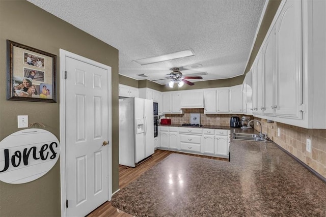 kitchen with black appliances, white cabinets, wood-type flooring, sink, and kitchen peninsula