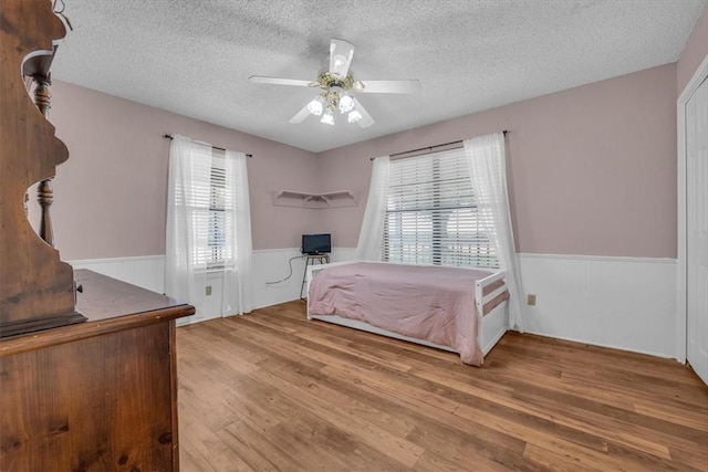 bedroom featuring hardwood / wood-style flooring, ceiling fan, and a textured ceiling