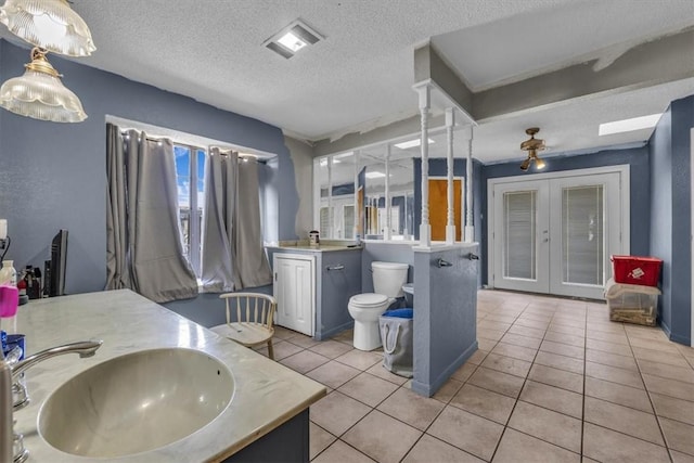 bathroom featuring tile patterned flooring, vanity, a healthy amount of sunlight, and toilet