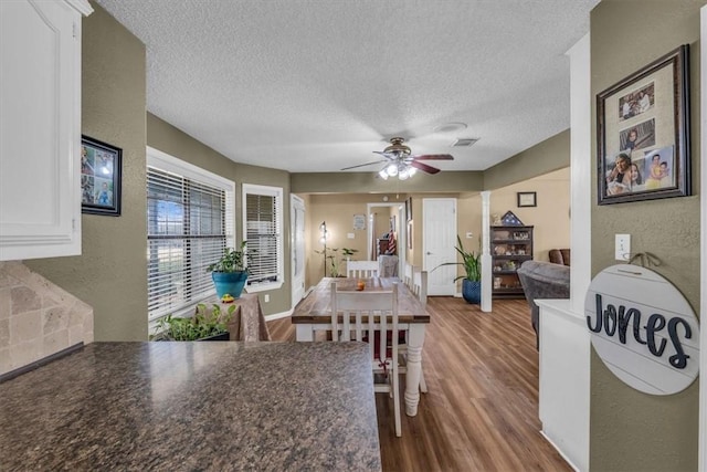 dining room featuring wood-type flooring, a textured ceiling, and ceiling fan