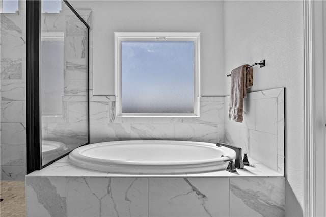 bathroom with a marble finish shower and a bath