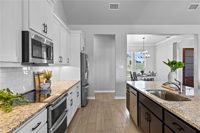 kitchen with tasteful backsplash, visible vents, stainless steel appliances, white cabinetry, and a sink