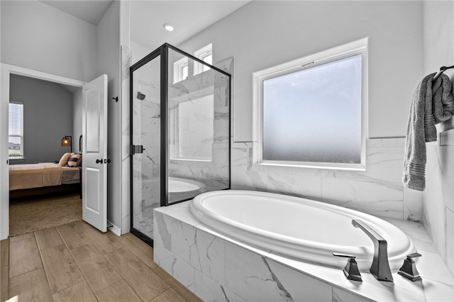 ensuite bathroom featuring a bath, wood finish floors, a marble finish shower, and ensuite bathroom