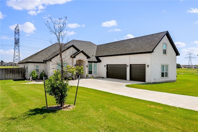 view of front of property featuring an attached garage, brick siding, a shingled roof, concrete driveway, and a front yard