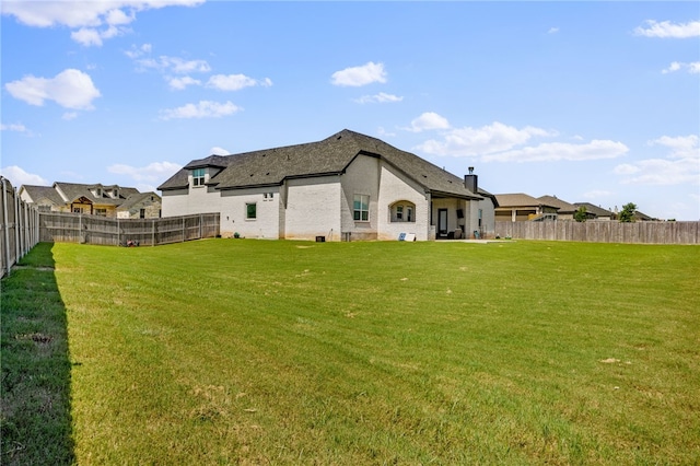 back of house with a fenced backyard and a yard