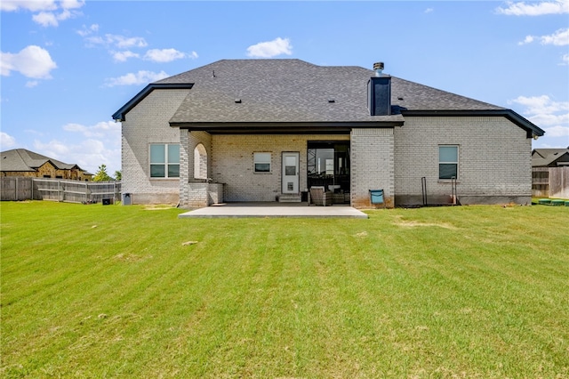 rear view of property featuring brick siding, fence, and a lawn