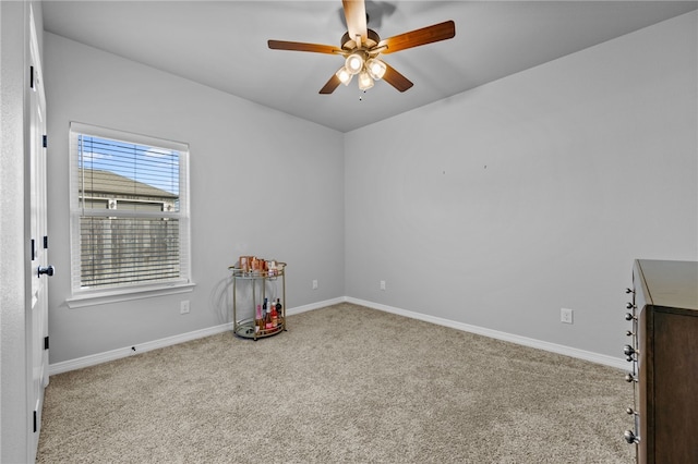 carpeted spare room featuring baseboards and a ceiling fan