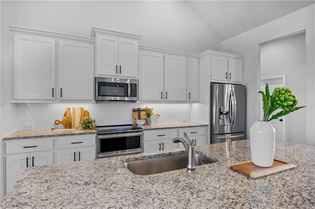 kitchen with lofted ceiling, appliances with stainless steel finishes, backsplash, and a sink