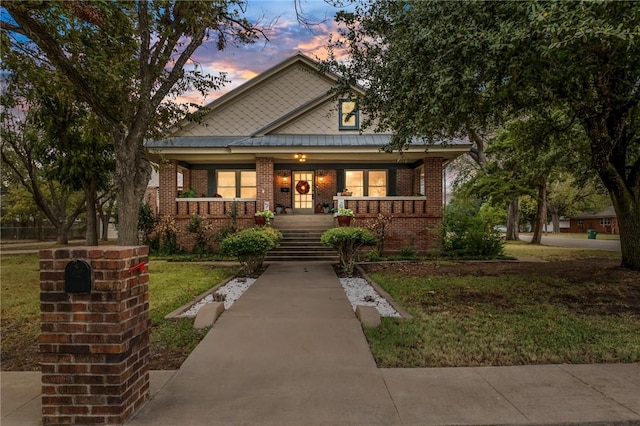 view of front of home with covered porch and a lawn