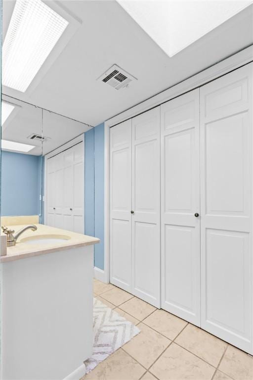 interior space with white cabinetry, light tile patterned floors, and sink