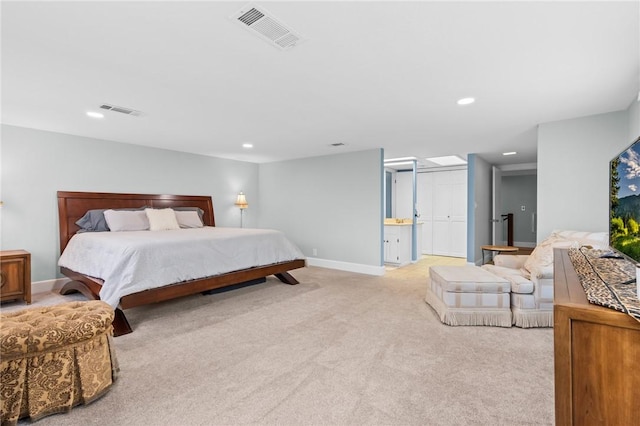 bedroom featuring ensuite bathroom and light colored carpet