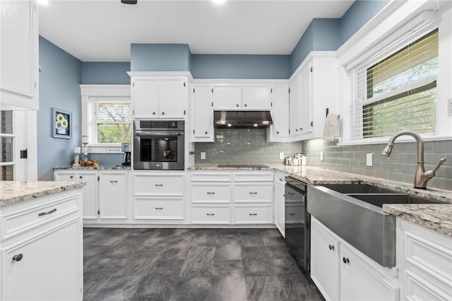 kitchen featuring tasteful backsplash, light stone counters, sink, black appliances, and white cabinets