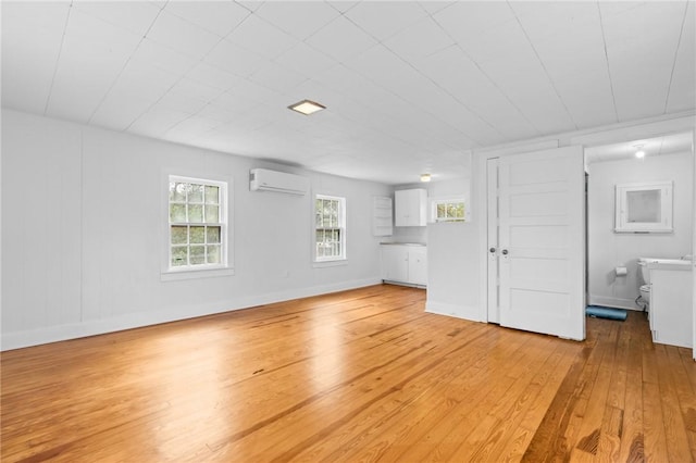 unfurnished living room featuring light hardwood / wood-style flooring and a wall mounted air conditioner