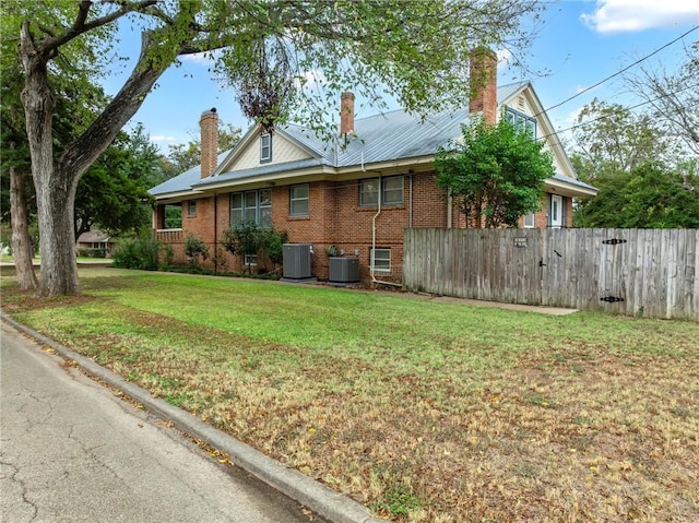 view of side of home with central AC unit and a yard