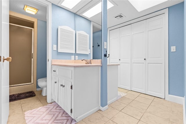 bathroom featuring toilet, vanity, tile patterned floors, and walk in shower