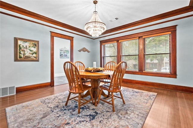 dining area with hardwood / wood-style flooring, a notable chandelier, and ornamental molding