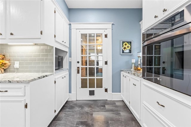 kitchen featuring decorative backsplash, light stone countertops, and white cabinetry