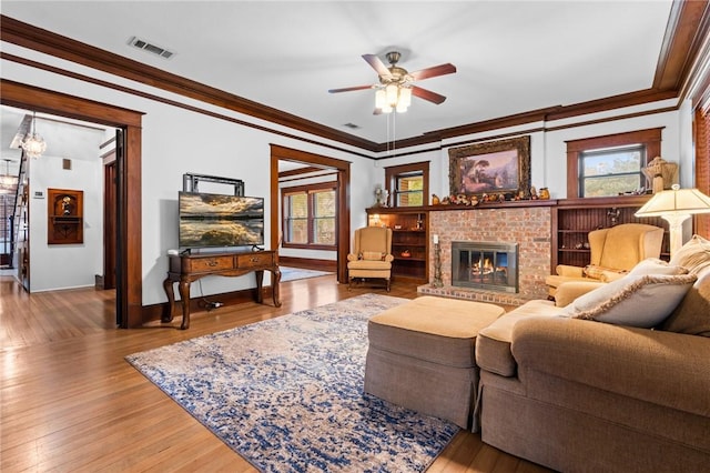 living room with hardwood / wood-style floors, ceiling fan, crown molding, and a fireplace