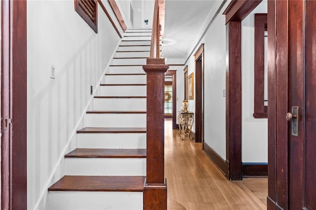 staircase with hardwood / wood-style floors and ornamental molding