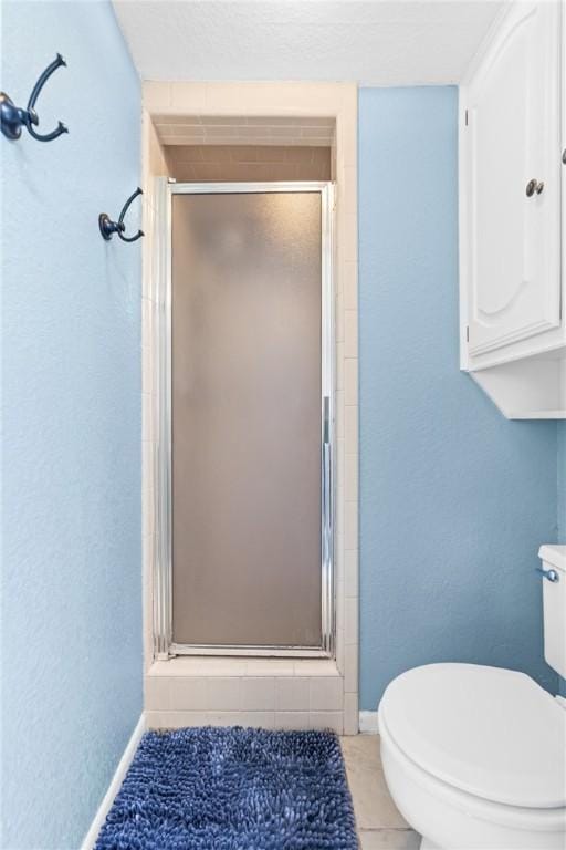 bathroom featuring tile patterned flooring, toilet, and a shower with door