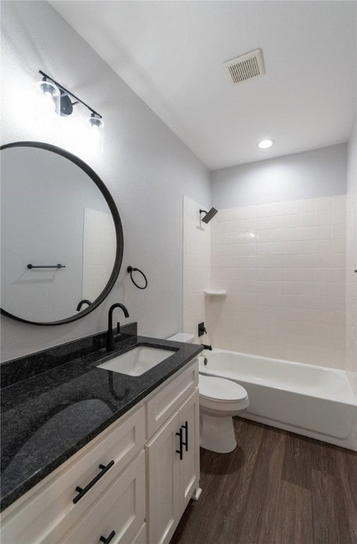 full bathroom with vanity, toilet, wood-type flooring, and tiled shower / bath